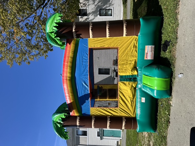 Tropical bounce house with green palm trees and a colorful arch