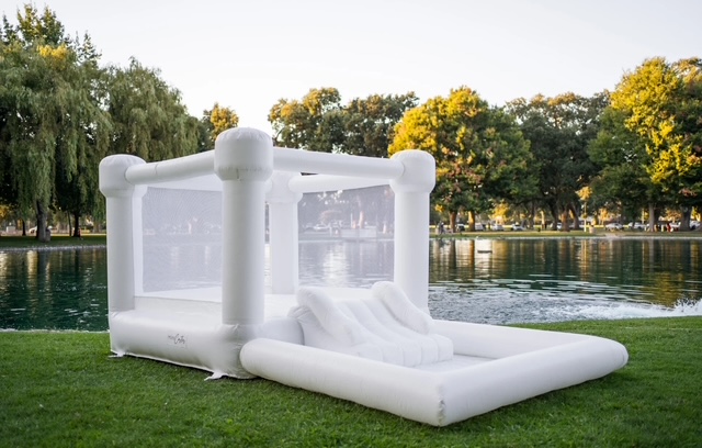 White inflatable bounce house set up on grass beside a pond